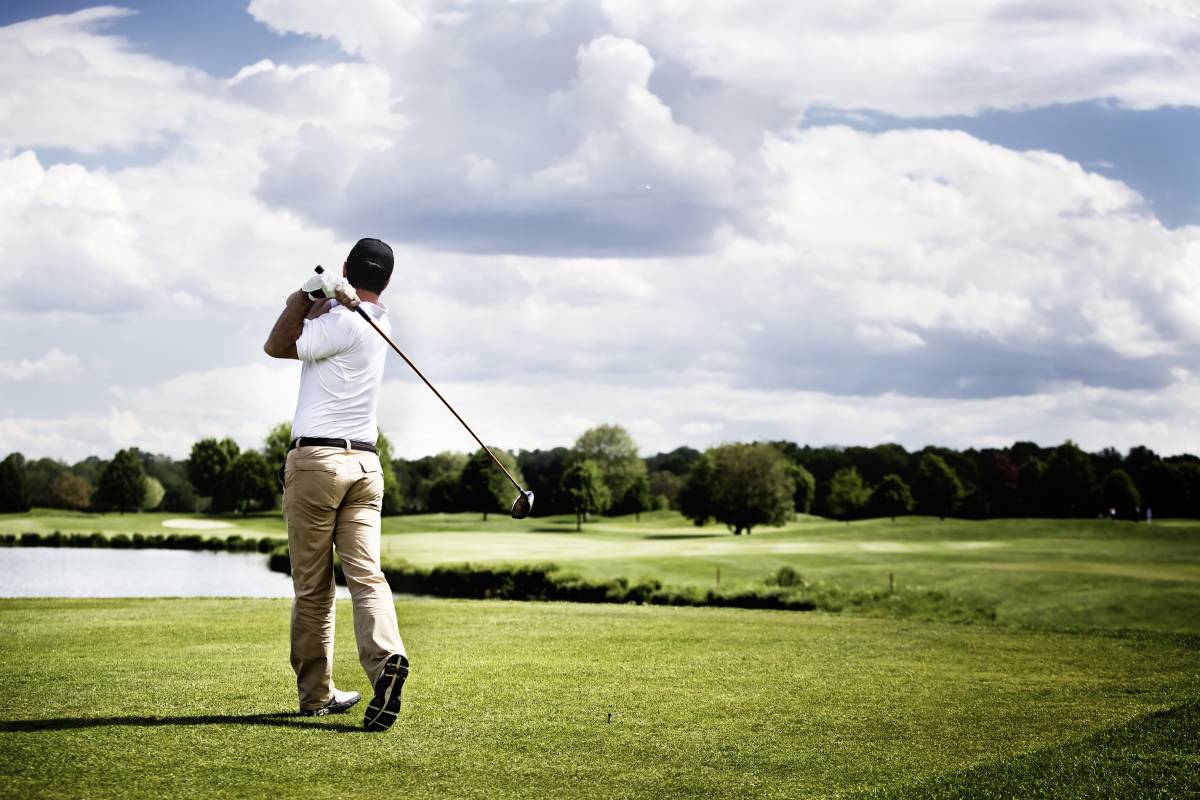 Male golf player teeing off golf ball from tee box