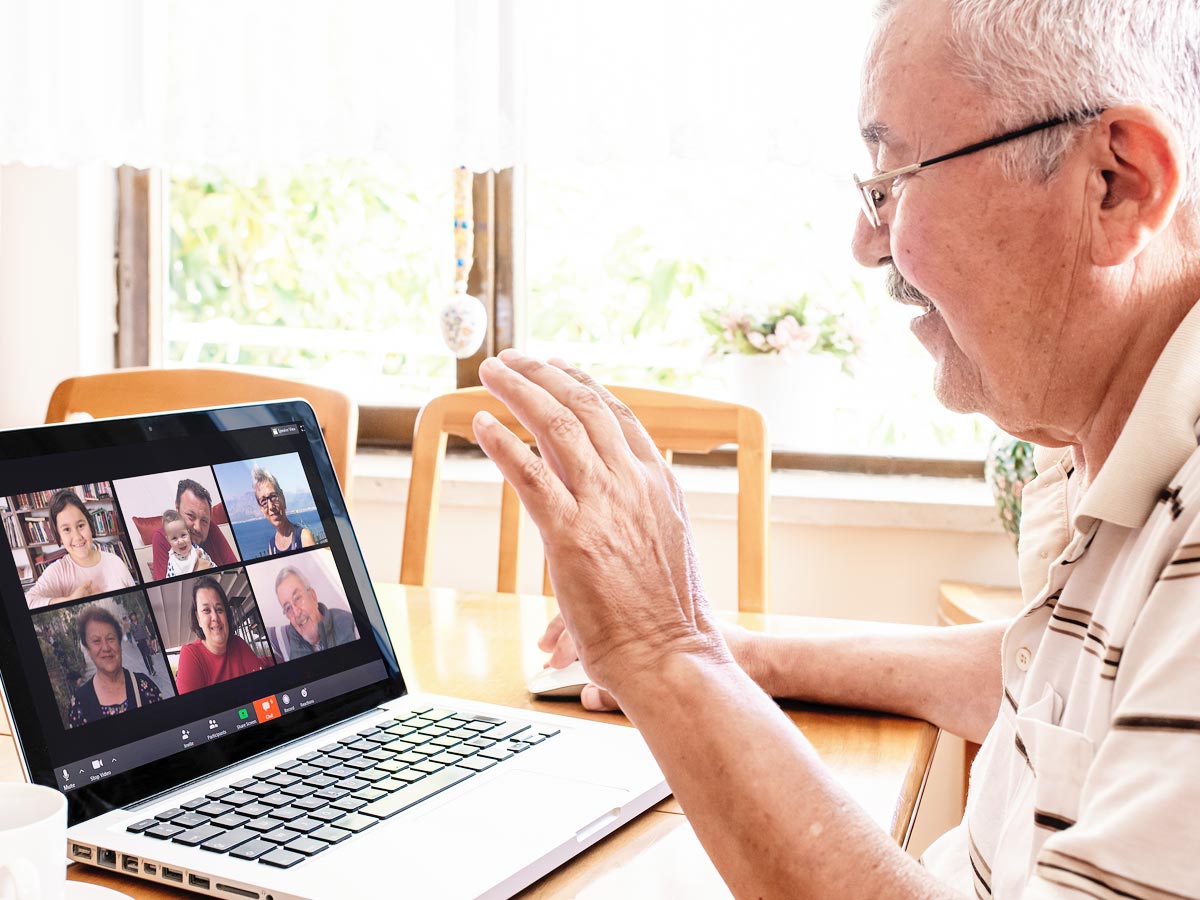 Senior man connecting with his family through a Zoom video conferencing app on his laptop