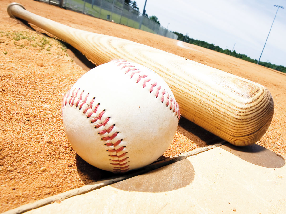 Close-up photo of a baseball and bat lying on the home plate