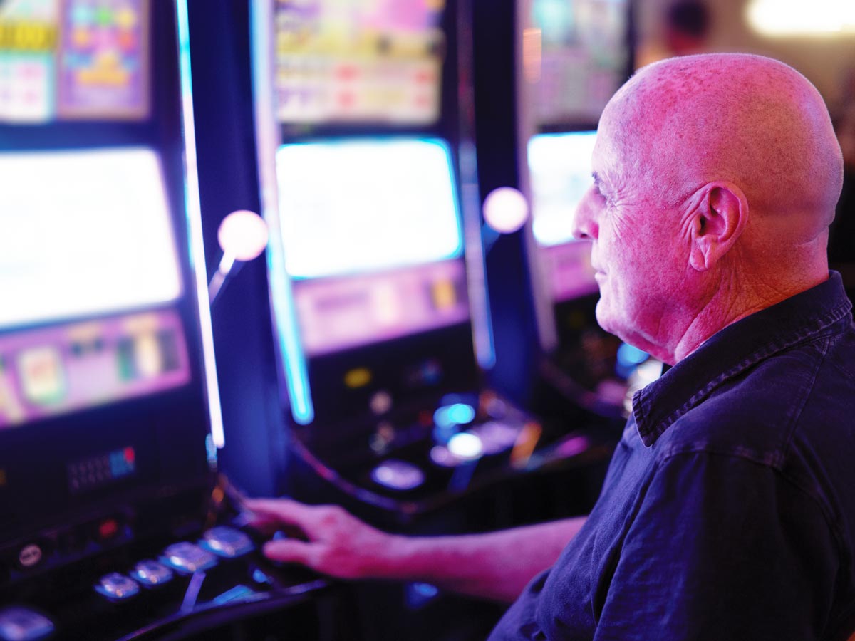 Photo of senior man sitting at a row of slot machines