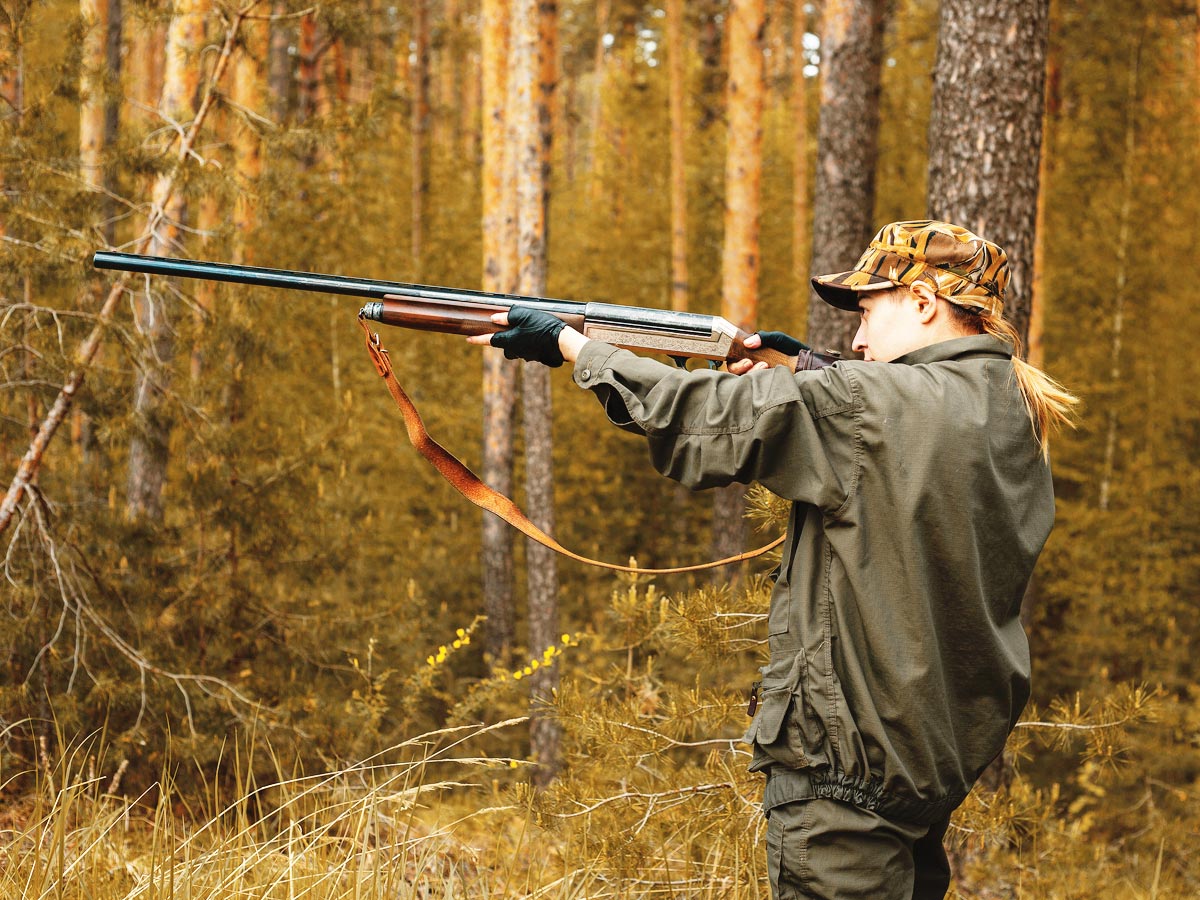 Photo of a female hunter taking aim with her rifle.