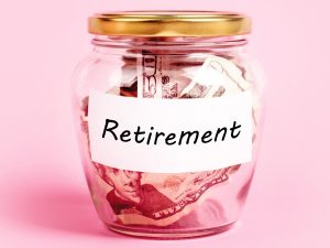 How Much Do You Need to Save for Retirement? Money in a jar labeled "Retirement" on a pink background