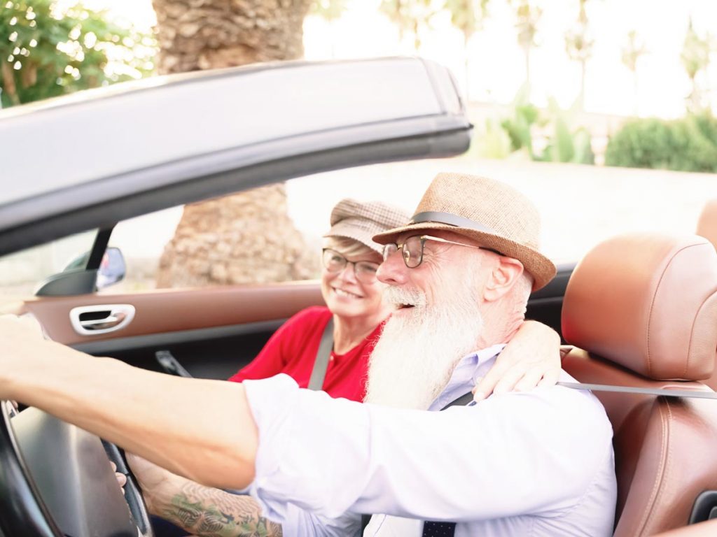 Photo of happy senior couple driving in a convertible. They are snowbirds.