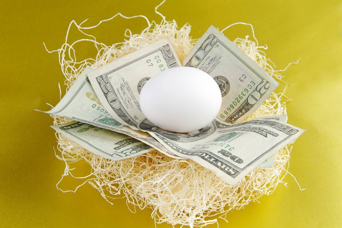 Photo of money and an egg on a yellow background, symbolizing a retirement nest egg