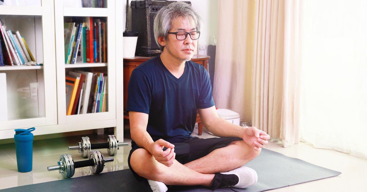Photo of senior man doing yoga on a yoga mat in his home