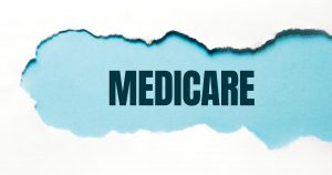 black "medicare" text on blue background revealed from a tear in white paper.