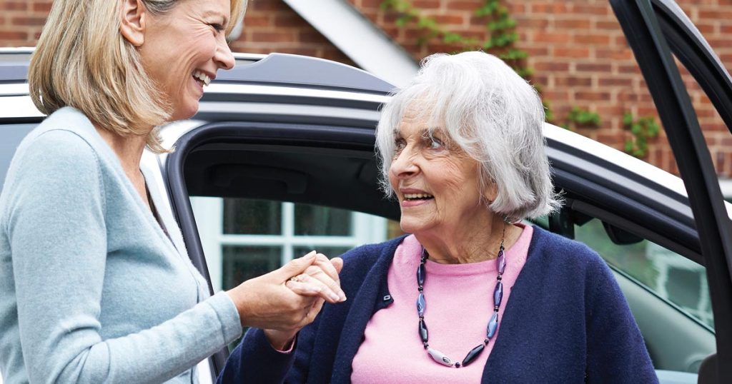 Photo of a woman helping a senior woman out of a car, for an article about planning for senior car travel.