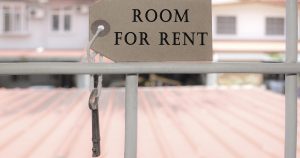 photo of a cardboard sign/tag that reads "ROOM FOR RENT" to represent home sharing,.