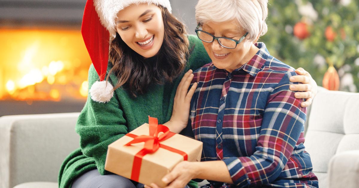 photo of a daughter and aging mother opening a Christmas gift