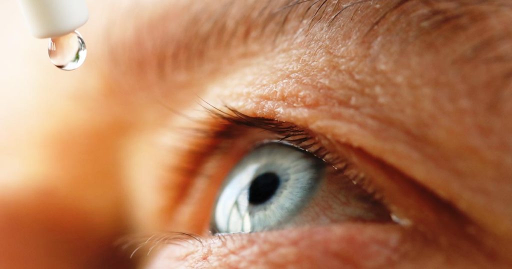 closeup photo of an elderly person putting eyedrops in their eye