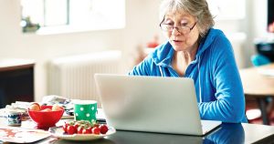 Photo of an elderly woman at home searching for health care providers on her laptop