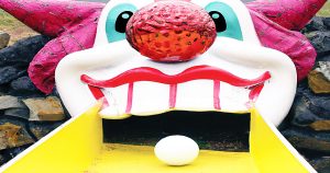 golf ball rolling into a clown mouth at a putt putt mini golf course